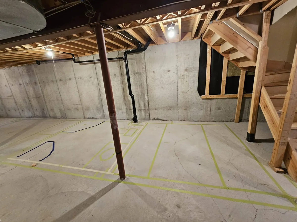 Unfinished basement with a bare concrete slab and poured concrete walls