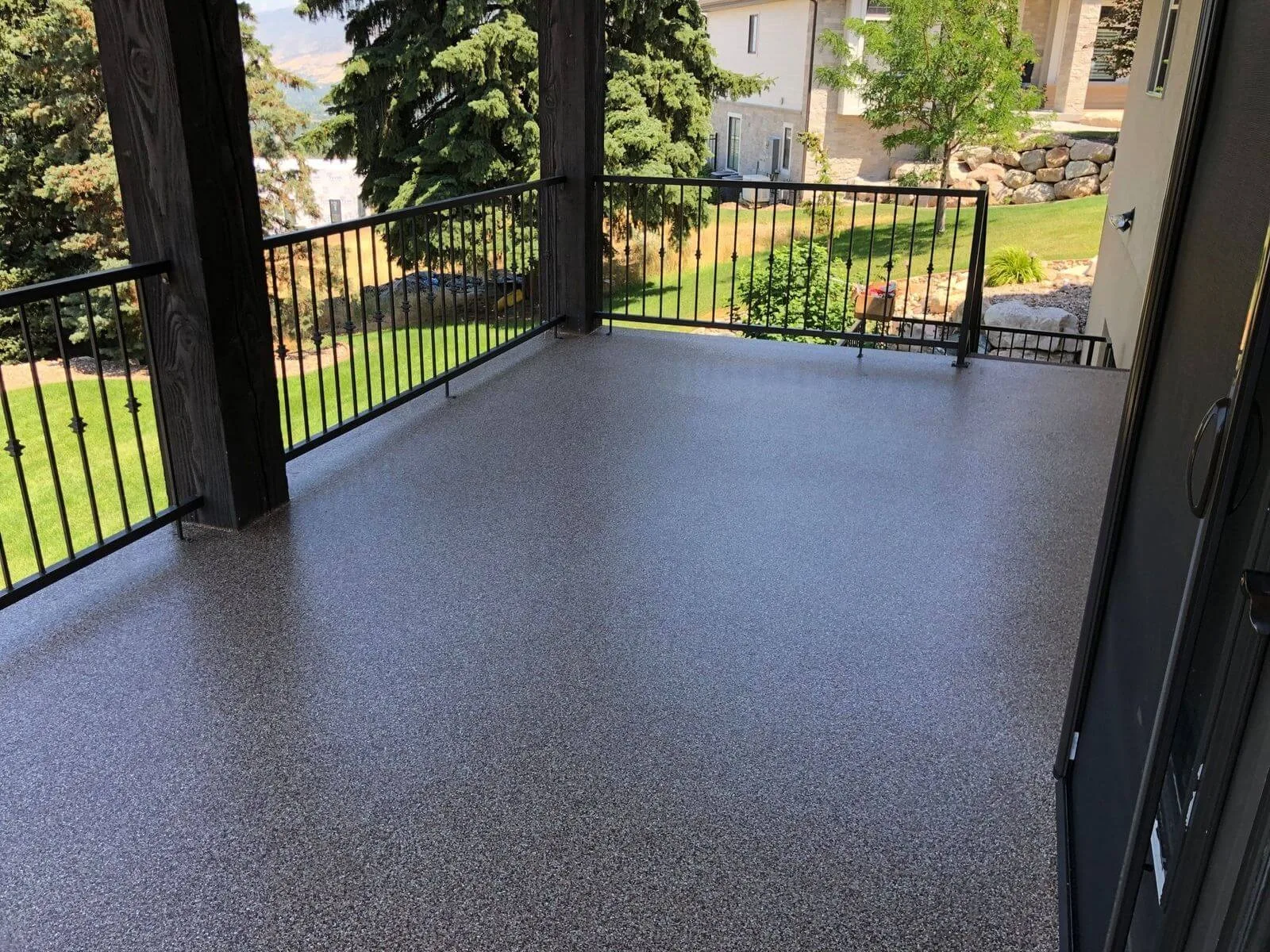 Coated deck with a metal railing and a view of the trees